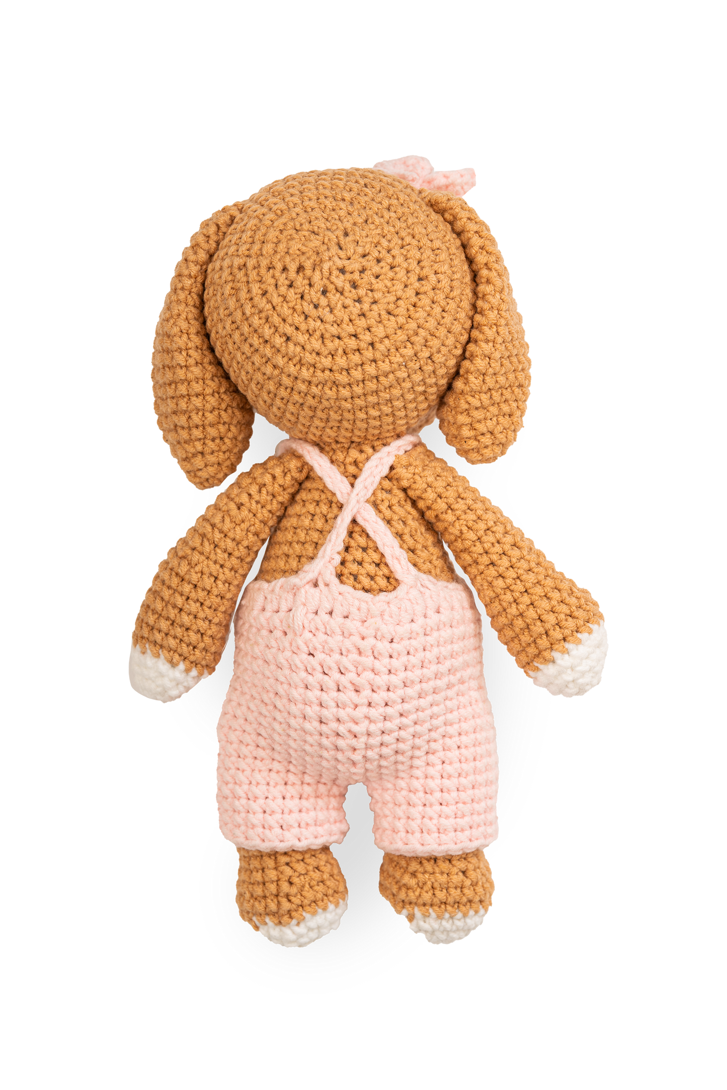 Back view of handmade crocheted puppy doll wearing soft pink overalls with crossed straps