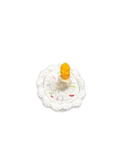 Top view of handmade crocheted birthday cake toy with white frosting, colourful sprinkles, and a single candle crafted by Knitted Friends