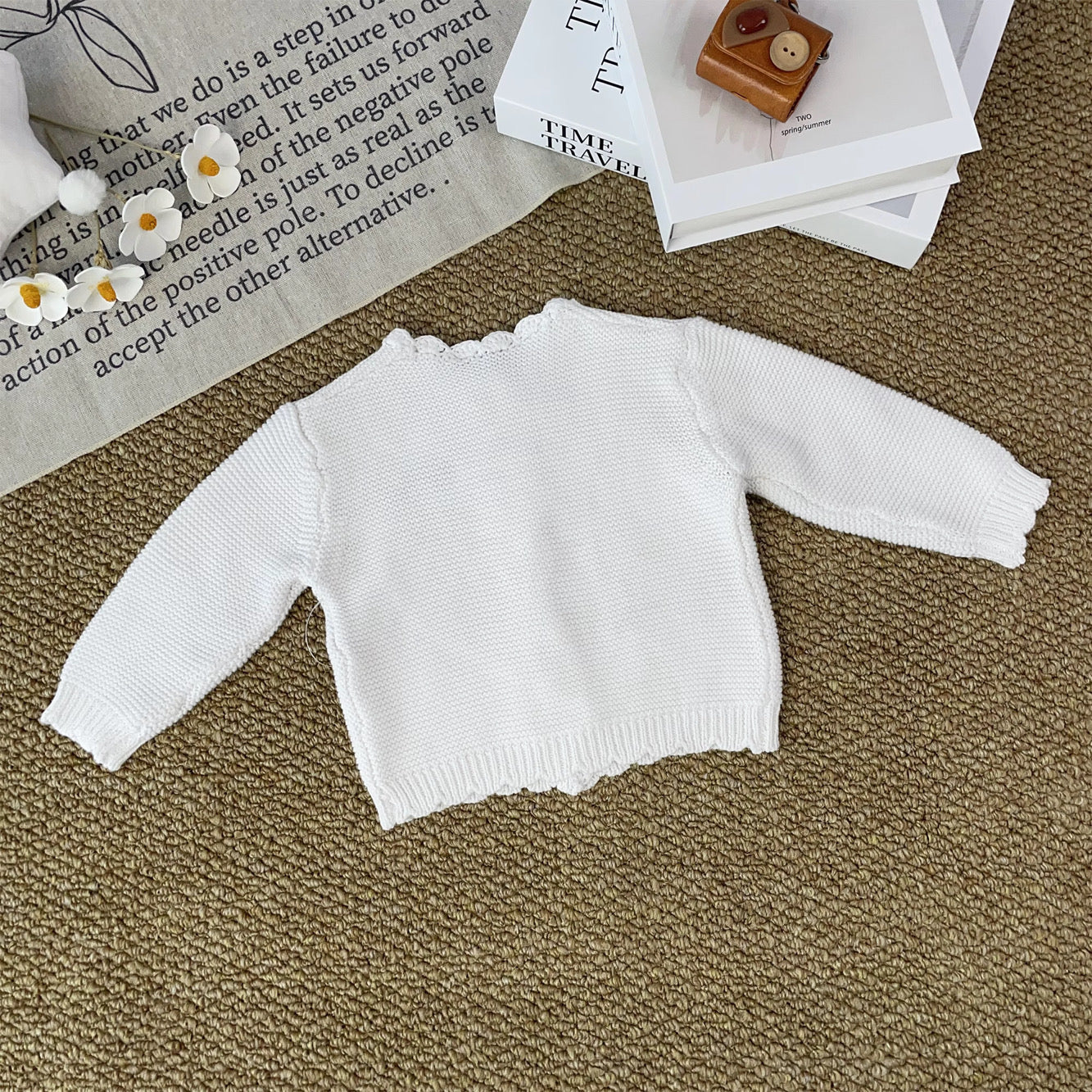 Knitted Friends white baby cardigan with scalloped edges and embroidered bear and bunny, wooden buttons, displayed in a nursery setting