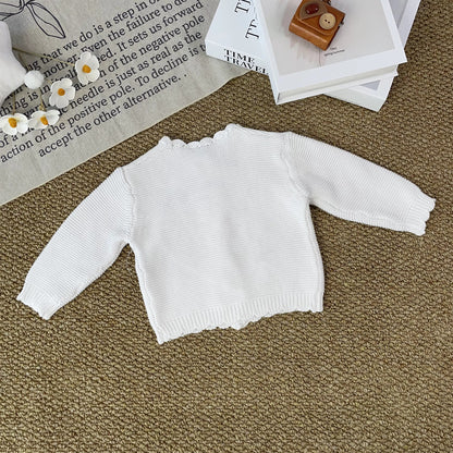 Knitted Friends white baby cardigan with scalloped edges and embroidered bear and bunny, wooden buttons, displayed in a nursery setting