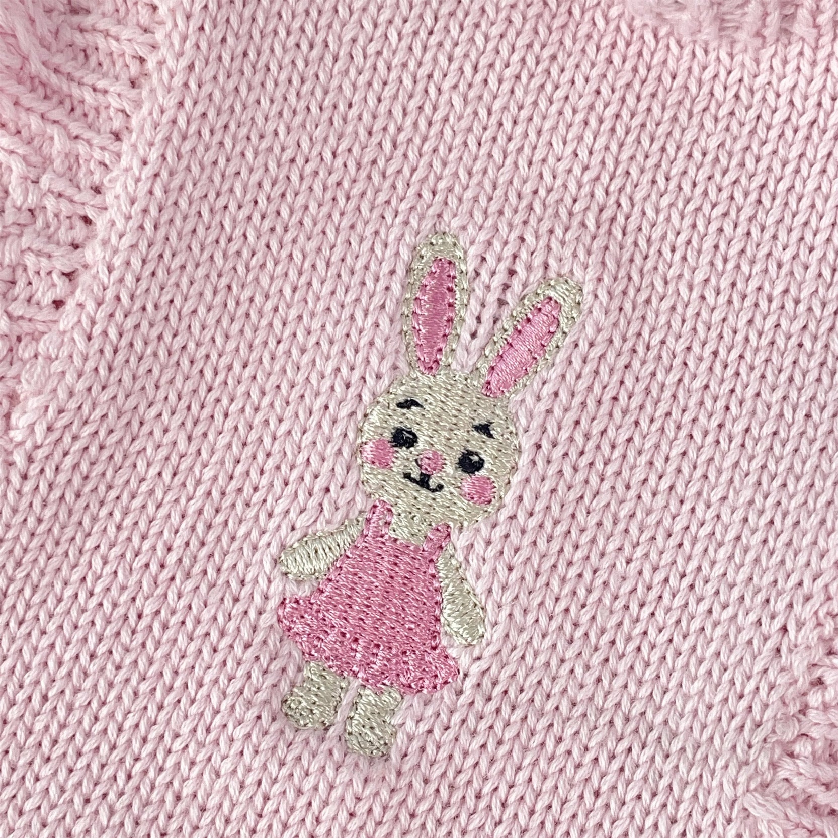 Knitted Friends pink baby tutu romper with ruffle straps, layered skirt, and embroidered bunny detail, displayed on a soft neutral background