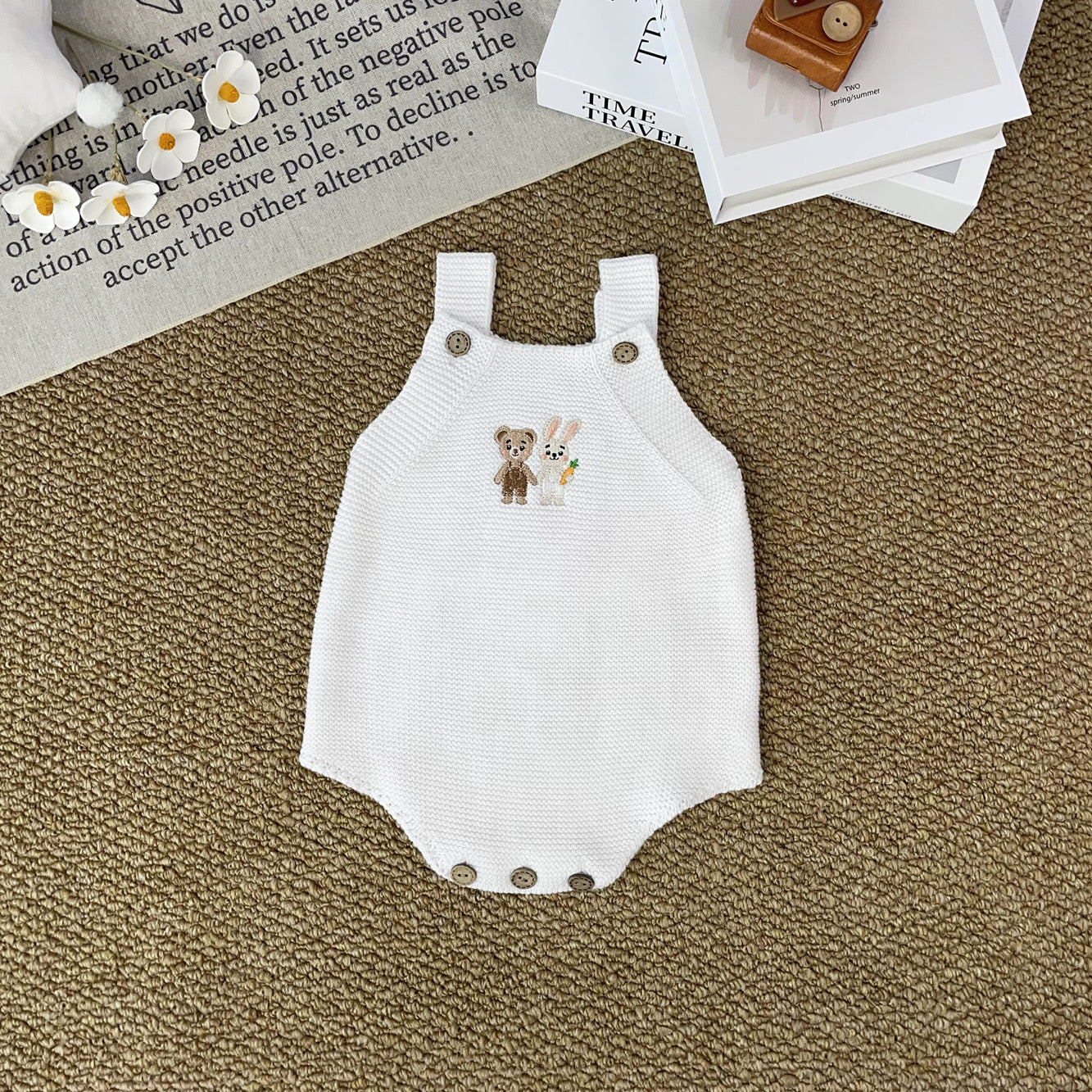 Knitted Friends white baby romper with embroidered bear and bunny, wooden button straps, displayed in a soft nursery setting