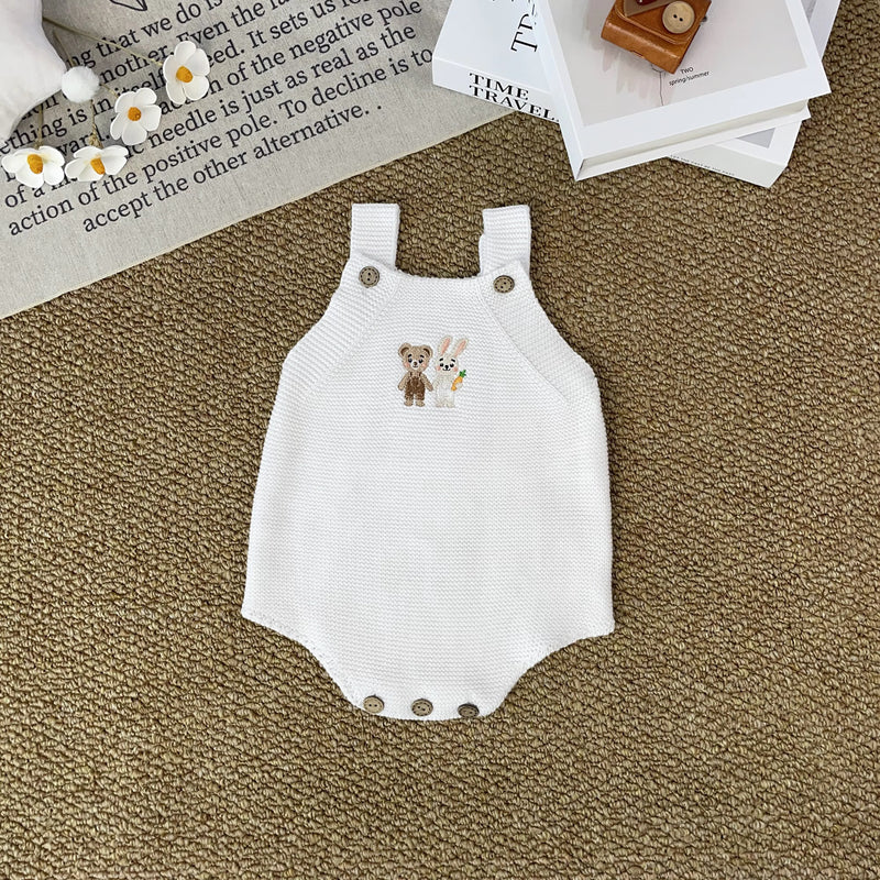 Knitted Friends white baby romper with embroidered bear and bunny, wooden button straps, displayed in a soft nursery setting