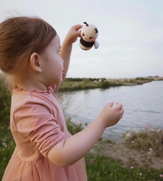 Young girl holding a handmade crochet bumblebee toy doll crafted by Knitted Friends