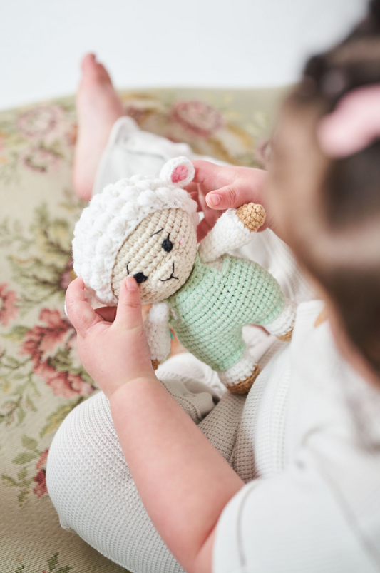 Child holding a soft crocheted baby sheep doll handmade by Knitted Friends