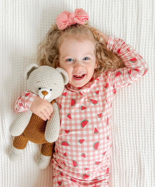 Smiling toddler holding a handmade crochet teddy bear toy crafted by Knitted Friends