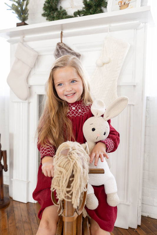 Child holding a handmade crochet bunny toy doll by Knitted Friends