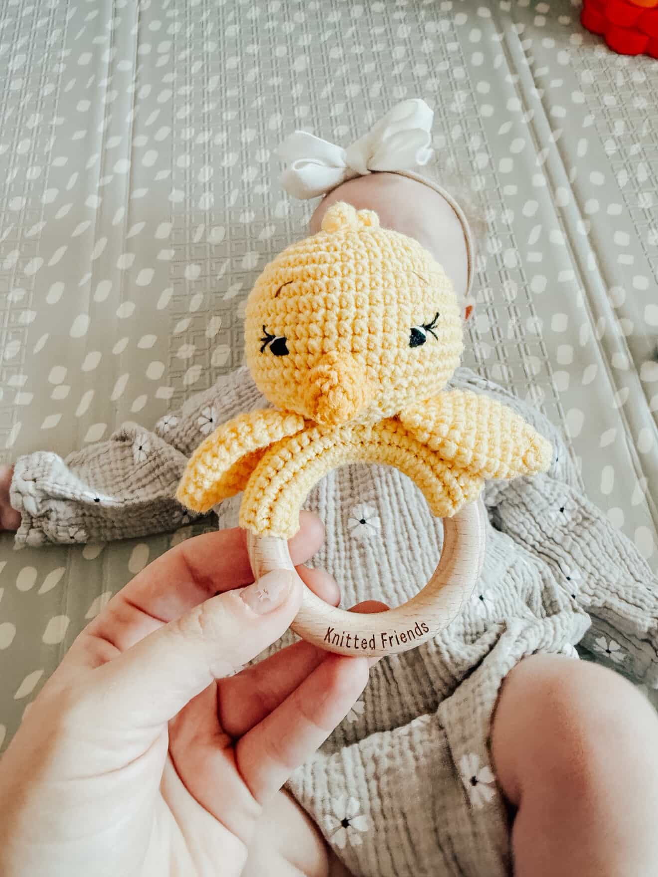 Hand holding a knitted chick rattle made by Knitted Friends