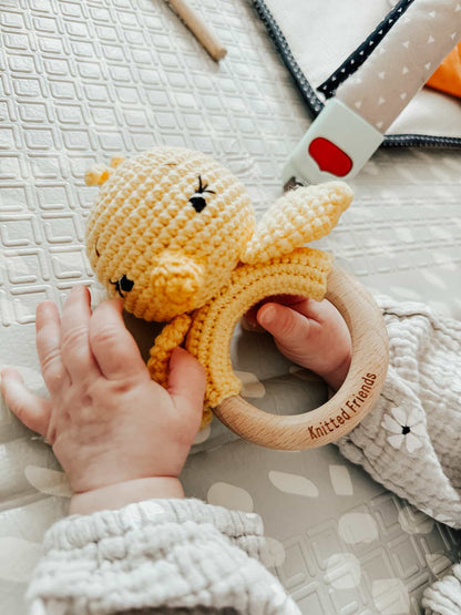 Baby holding a handmade knitted chick rattle with a wooden ring by Knitted Friends