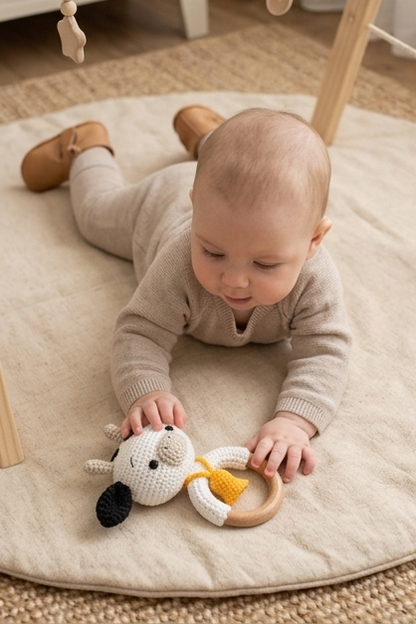 Baby playing with a crochet cow rattle by Knitted Friends