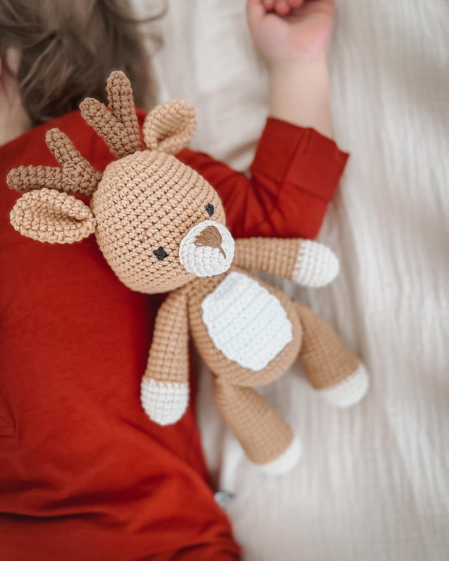 Knitted Friends handmade deer doll in organic cotton, shown beside a child in a cosy setting