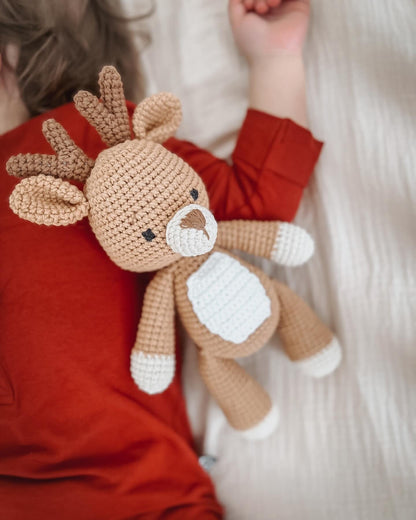 Knitted Friends handmade deer doll in organic cotton, shown beside a child in a cosy setting