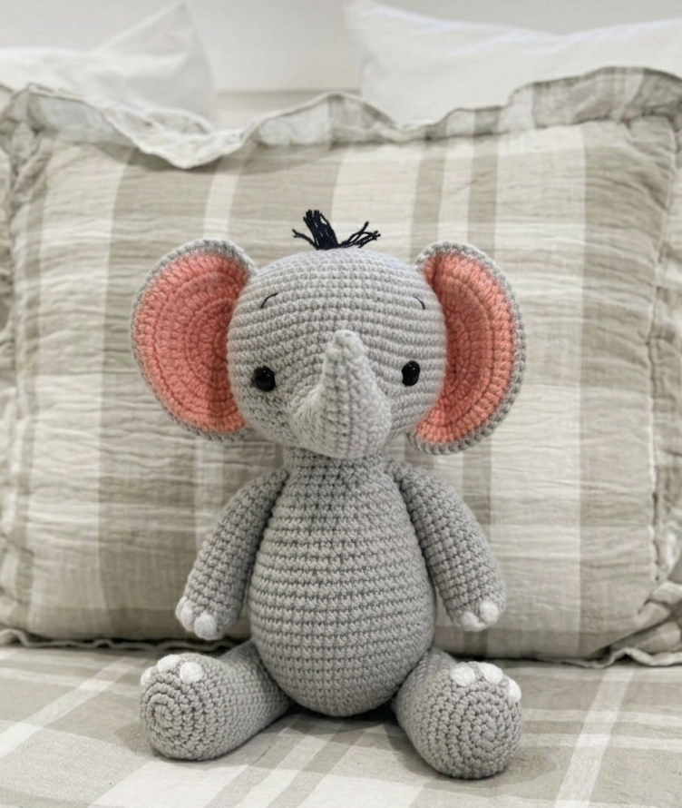 Handmade crochet elephant plush toy by Knitted Friends with soft grey yarn, pink-lined ears