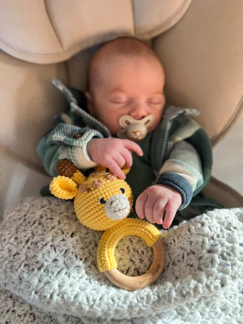 Baby sleeping with a giraffe rattle made by Knitted Friends
