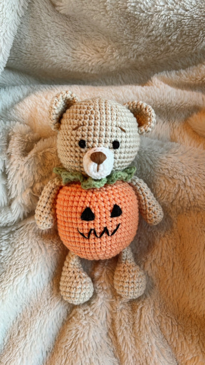 Knitted Friends pumpkin bear doll with crochet texture and Halloween pumpkin body, displayed on a black background