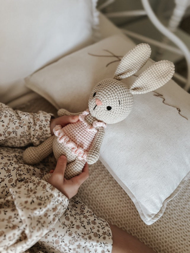 Handmade crochet bunny doll with pink tutu, organic cotton stuffed toy by Knitted Friends, held by a child