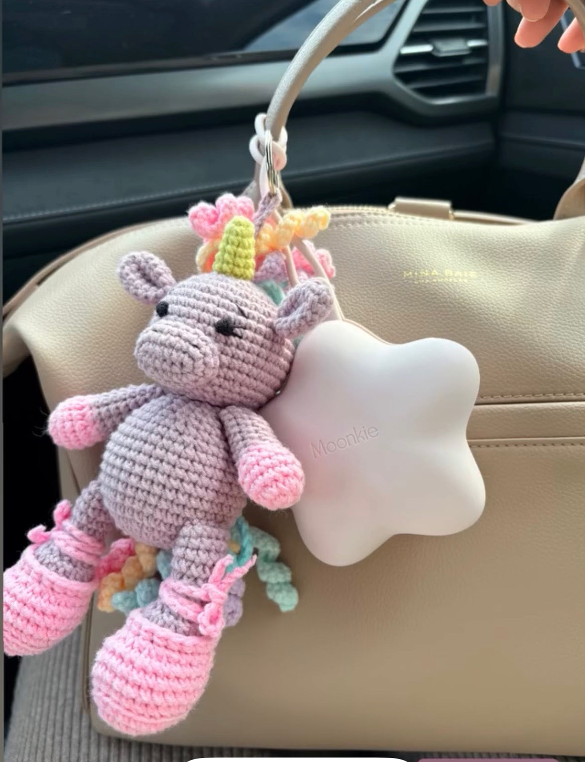 Handmade crochet unicorn bag charm attached to a handbag made by Knitted Friends