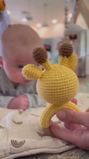 A video of a baby with giraffe rattle by Knitted Friends